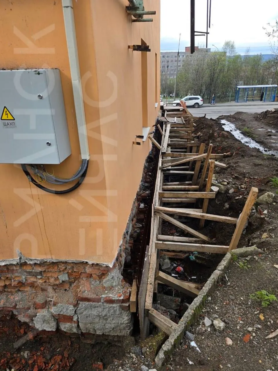 Внешне дом выглядит ухоженно, но уже больше года у здания раскопан фундамент: талая вода с сопки уходит под дом, жильцы жалуются на сырость и тёмные подъезды.