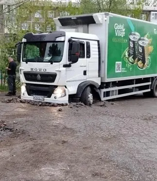 Передними колесами грузовик ушёл в провал грунта между домами на улице Коммунальная; коммунальные службы огородят яму, администрация направила погрузчик.