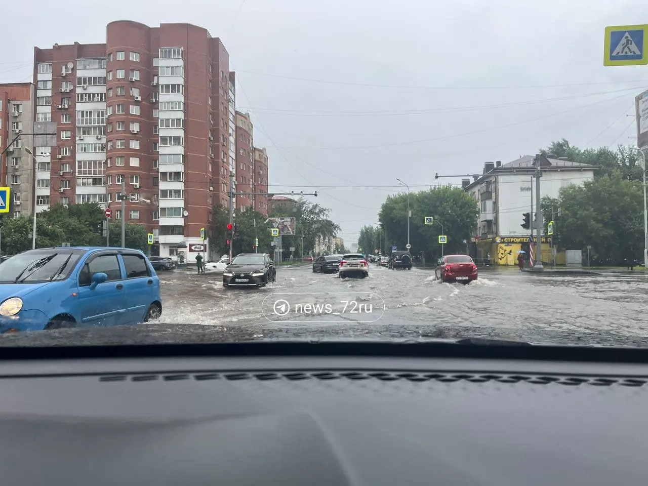 Из-за подтопления движение осложнено: пешеходы идут по колено в воде, часть людей передвигается на самокатах, а автомобили с низким клиренсом едут с включённой аварийкой. На мосту также не работает светофор.