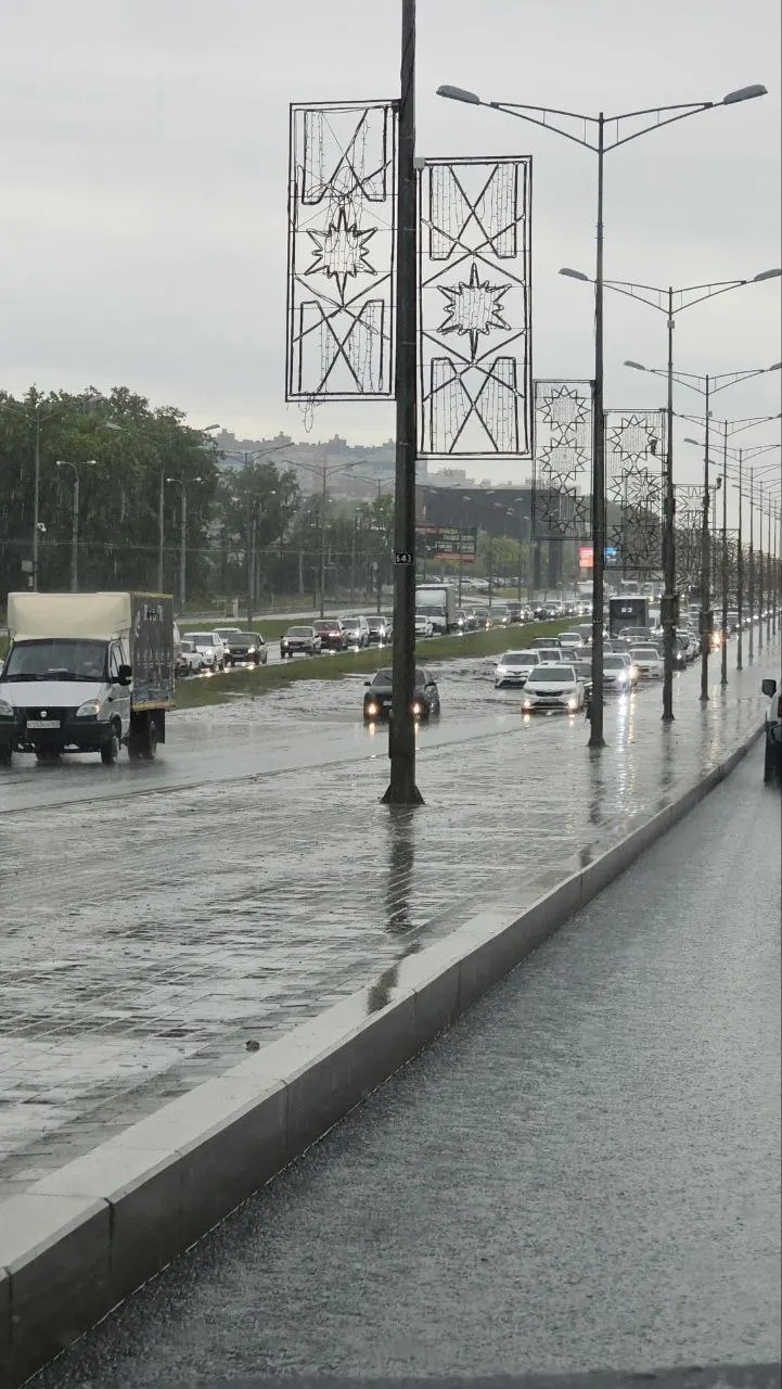 На Московском шоссе перед Ракитовским шоссе образовалась пробка из‑за крупных луж: вода затрудняет движение, а местные отмечают, что ливнёвки не справляются или отсутствуют.