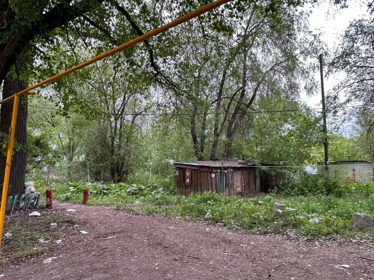 В доме №19 на ул. Земца часть квартир расселена, но во второй половине до сих пор остаются жильцы — в том числе пенсионеры — без горячей воды и с еле текущей холодной; с крыши падают обломки, а территория вокруг заросла и горит.